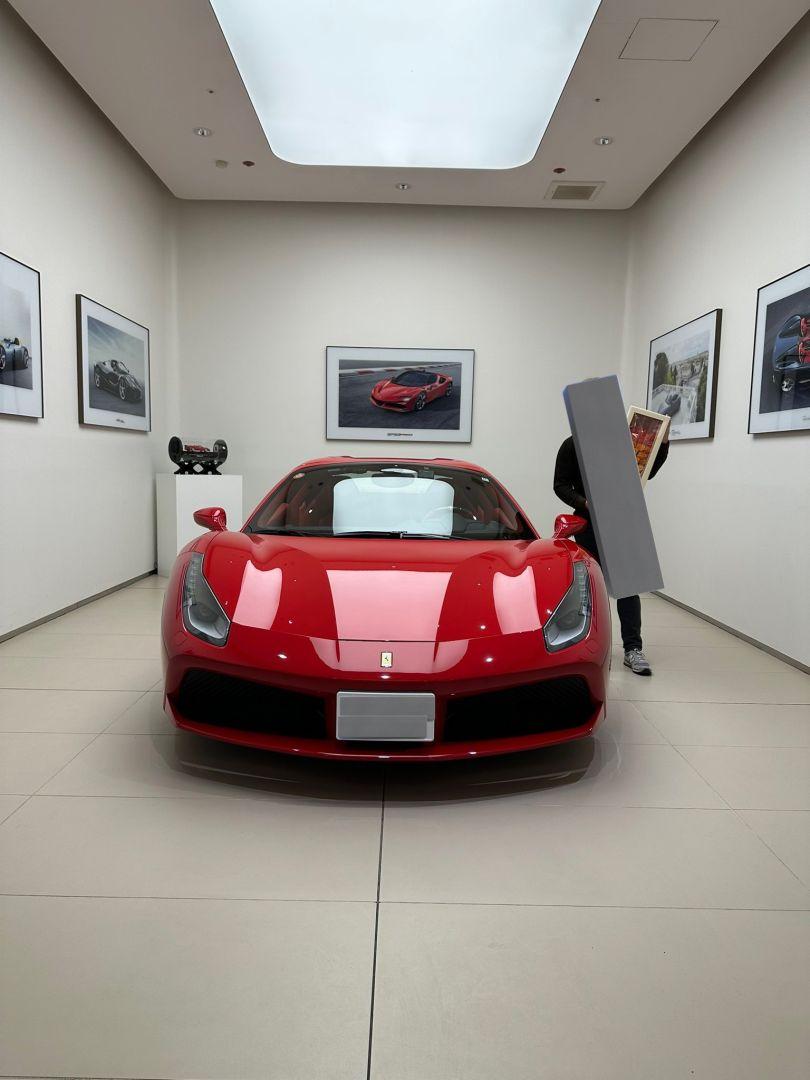 Manno posant fièrement à côté de sa nouvelle Ferrari, symbole de son succès